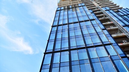 View of a skyscraper under construction. Modern architecture background. Building a high-rise building,  the concept of real estate construction. 