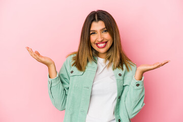 Young indian woman isolated on pink background showing a welcome expression.