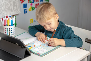 online training. the boy sits at the computer in the room and does his homework