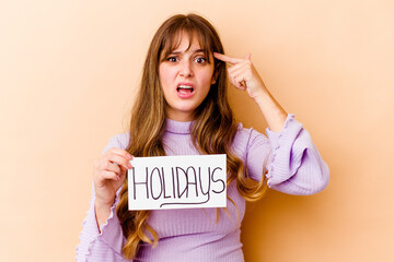 Fototapeta na wymiar Young caucasian woman holding a Holidays placard isolated showing a disappointment gesture with forefinger.