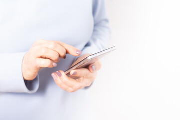 Elderly hands holding mobile cell phone. Unrecognizable old woman browsing news feed at cellphone. Blurred background. Looking at mobile screen. Close-up. 