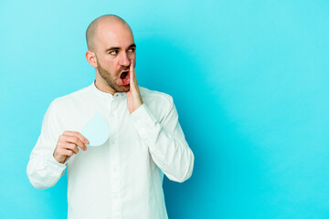 Young caucasian bald man celebrating world water day isolated on blue background is saying a secret hot braking news and looking aside