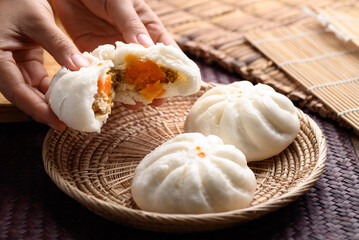 Steamed buns stuffed with minced pork and salted egg holding by hand and eating, Asian food