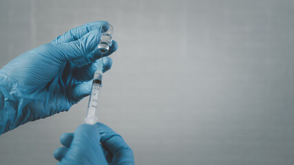 Doctor wear hand in blue gloves holding a syringe with liquid vaccines for children or older adults,Concept fight against virus covid-19 corona virus