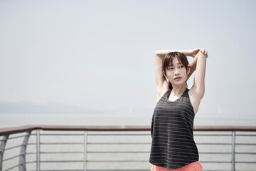 Obraz premium young asian woman stretching arms outdoors