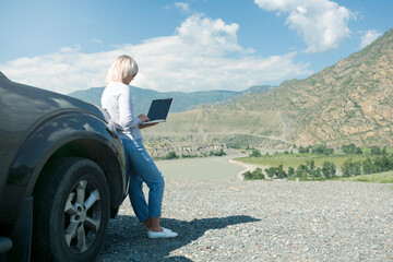 Caucasian Woman With Modern Laptop Computer In His Hands Working Remotely During Automobile Trip At Mountains.