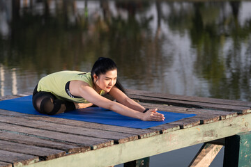 Fototapeta na wymiar Young beautiful Asian woman in sports outfits doing yoga outdoor in the park in the morning with warm sunlight for a healthy lifestyle. Young woman yogi doing yoga in morning park