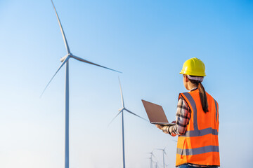 female engineer working with laptop computer against wind turbine farm © geargodz