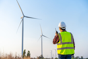 male engineer using walkie talkie to checking system against wind turbine farm