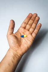capsule in yellow and blue color, on palm of the hand, general plane