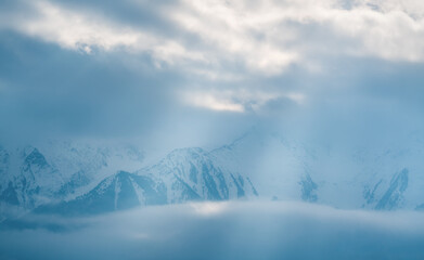 Mountain peaks covered with snow between clouds with bright sunrays shining through, Mieminger Plateau, Tirol, Austria