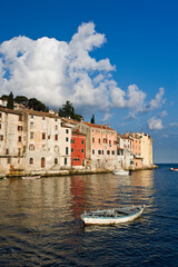 Obraz premium Small boat and buildings reflecting on the Adriatic Sea at sunrise, Rovigno, Croatia