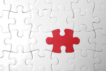 White jigsaw puzzles and red one as background, top view
