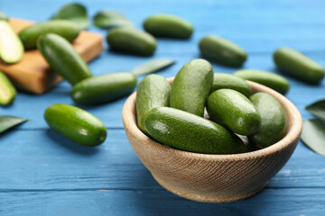Fresh seedless avocados in bowl on blue wooden table, closeup