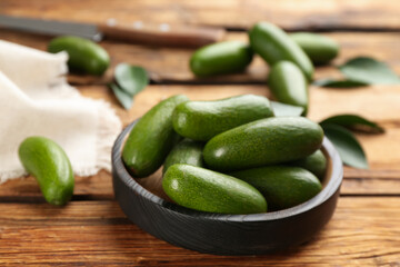 Fresh avocados with green leaves on wooden table, closeup