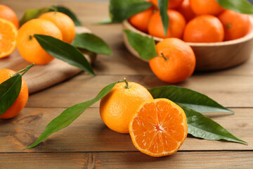 Fresh ripe tangerines with green leaves on wooden table