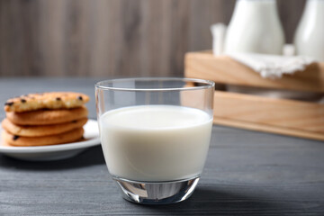 Glass of delicious milk on grey wooden table