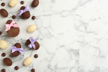 Fototapeta na wymiar Sweet chocolate eggs and candies on white marble table, flat lay. Space for text