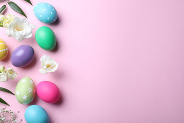Bright painted eggs and flowers on pink background, flat lay with space for text. Happy Easter