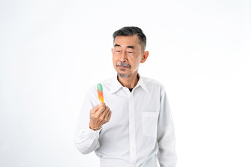 A cheerful old Asian man in a white shirt, pleased with a colorful popsicle. Shoot On a white background in the studio. Active, senior, and elderly concept