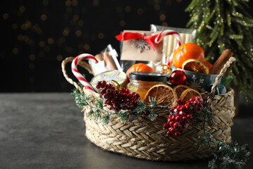 Wicker basket with gift set and Christmas decor on grey table. Space for text