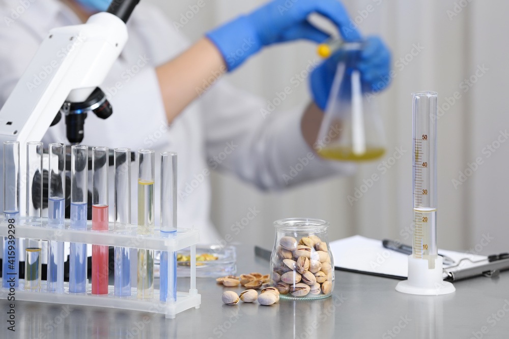 Wall mural pistachios on table and scientist proceeding quality control in laboratory