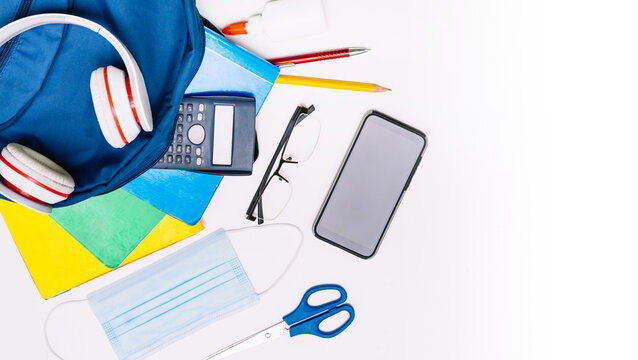 School supplies for school, notebooks, pens, scissors and a mask.