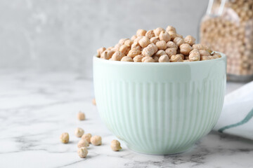 Chickpeas in bowl on white marble table, space for text