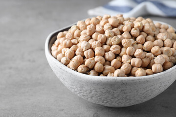 Raw chickpeas in bowl on grey table, closeup