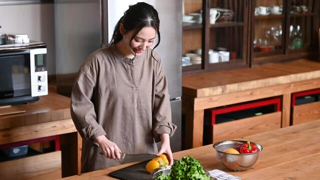キッチンで野菜の下ごしらえや料理をする美しい日本人女性の動画