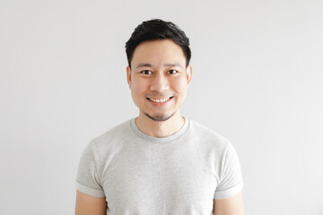 Smile face of happy Asian man wear grey t-shirt and on grey background.