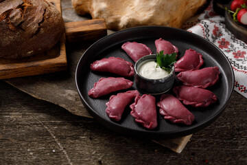 Delicious traditional Russian dumplings, handmade dough painted with beets. Still life on a wooden board. Close-up.
