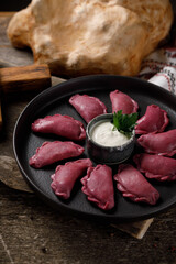 Delicious traditional Russian dumplings, handmade dough painted with beets. Still life on a wooden board. Close-up.