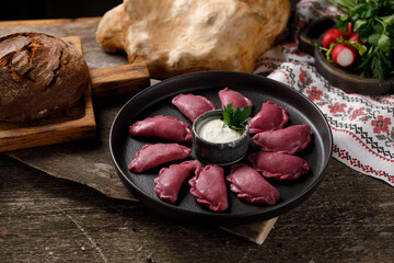 Delicious traditional Russian dumplings, handmade dough painted with beets. Still life on a wooden...
