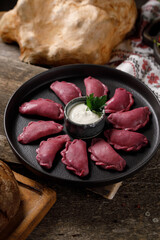 Delicious traditional Russian dumplings, handmade dough painted with beets. Still life on a wooden board. Close-up.
