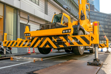 工事現場でアウトリガー使用中のクレーン車