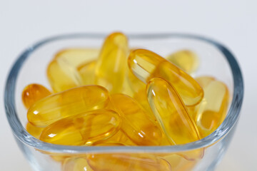 fish oil pills with omega 3 in a glass bowl on white background