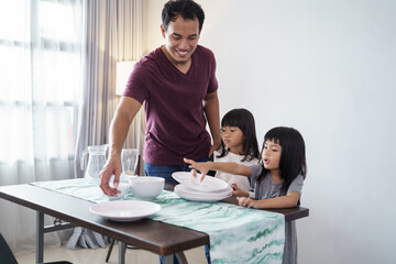 portrait of asian Father and small daughter preparing dining table for dinner