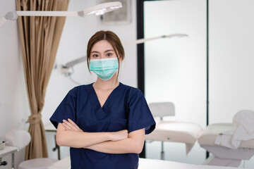 Fototapeta na wymiar Beauty clinic and health concept. Confident woman physician Wearing protective medical mask and crossing arms on her chest posing and smile friendly with copy space for your advertising information.