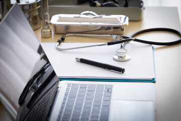 The stethoscope was placed on a doctor's desk with a notebook, pen and notepad, selective focus.