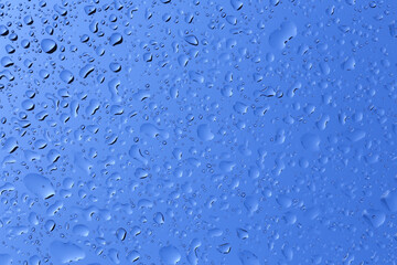 Water droplets condense on glass in the blue background.
