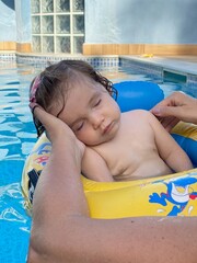 Bebe dorme na piscina apoiada nas nação de sua mãe 