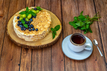 Obraz na płótnie Canvas Homemade Napoleon cake (Mille-feuille) decorated with grapes, blueberries and mint leaves on a wooden table. 