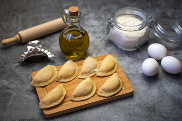 Raw dumplings (vareniki) with potato made at home. Traditional Russian dumplings on a wooden board.