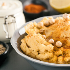 Homemade hummus with olive oil in gray bowl and ingredients. Traditional middle eastern appetizer hummus on gray background - healthy vegan paste snack. Vegetarian diet,nutrition protein food concept