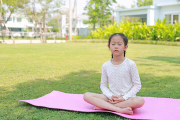 Asian little child girl sitting meditation in the garden. Kid Meditate in the park