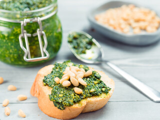 Close up view of baguette bread with fresh basil pesto sauce on gray wooden table. Copy space.