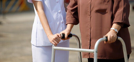 Nurse is helping Senior Elderly Asian Woman uses Zimmer frame walker
