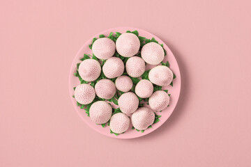 White strawberries in a plate on a light pink background. Top view.