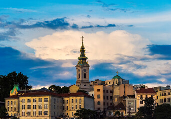 Obraz premium Saint Nicholas Church and buildings by the Danube River at sunset, Belgrade, Serbia